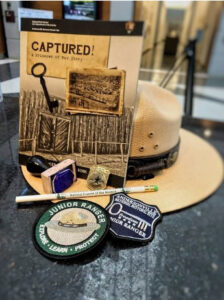 Booklet, hat and patches on a table top. 